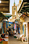  Alley in the souk with fabrics and scarves and view of the Mosque Souk el-Blat in the Medina in Tunis, Tunisia 