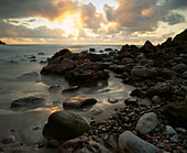 Waves of the Atlantic Ocean gently lap over rocks on the shoreline at sunset, near Mirleft in Sud Agadir,Morocco.