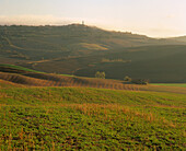 After dawn the mist rises and a warm sunlight envelops the fields and valleys around the hilltop town of Pienza.