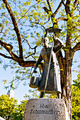  Bronze statue of Ida Schumacher at the Viktualienmarkt and view of the Alter Peter (St. Peter) in Munich, Bavaria, Germany 