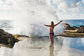 Girl in the foam of a wave at Blowhole beach at Pointe des Chateaux, Grande-Terre, Guadeloupe, overseas region of France,Leewards Islands, Lesser Antilles, Caribbean