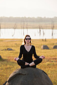 Young woman practising yoga posture by the Senanayake Samudraya Lake, Gal Oya National Park, Sri Lanka, Indian subcontinent, South Asia