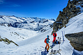 Zwei Personen auf Skitour stehen in der Rosskarscharte, Zillertaler Alpen, Salzburg, Österreich