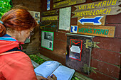  Woman hiking, signing the Rheinsteig book, Grenzvogt, Rheinsteig, Rhenish Slate Mountains, UNESO World Heritage Upper Middle Rhine Valley, Rhineland-Palatinate, Germany 