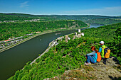  Man and woman hiking looking at the Rhine and the castles Sterrenberg and Liebenstein, Brömserkopf, Rheinsteig, Rhenish Slate Mountains, UNESO World Heritage Upper Middle Rhine Valley, Rhineland-Palatinate, Germany 