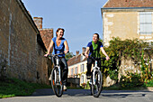 Young women cycling in the village of Villeray,Commune of Condeau,Orne department,Lower Normandy region,France,Western Europe