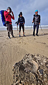 Drei Personen beim Wandern stehen vor Versteinerung am Strand, Port Edwards, Wild Coast Trail, Wild Coast, Eastern Cape, Südafrika