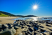  Two people hiking across a sandy beach on the Indian Ocean with boulders in the foreground, Wild Coast Trail, Wild Coast, Eastern Cape, South Africa 