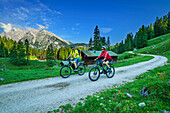  Man and woman mountain biking towards the Gotzenalm, Watzmann mountain in the background, Berchtesgaden National Park, Berchtesgaden Alps, Berchtesgaden, Upper Bavaria, Bavaria, Germany 