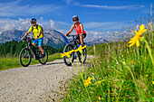 Mann und Frau beim Mountainbiken zur Gotzenalm, Steinernes Meer im Hintergrund, Nationalpark Berchtesgaden, Berchtesgadener Alpen, Berchtesgaden, Oberbayern, Bayern, Deutschland