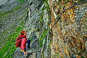  Woman hiking up a secured rock face, Valmalenco, Alta via della Valmalenco, Bernina Alps, Lombardy, Italy 