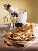 Plate of oysters & lemon on ice, bread & champagne on table