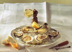 Oysters and lemon on ice on plate, wine glass on table