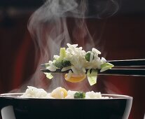Dampfender Reis mit Gemüse auf Stäbchen über Reisschale