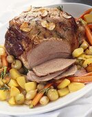 Leg of lamb with roasted garlic slices on vegetables