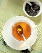 Cup of tea with tea spoon, with tea leaves behind