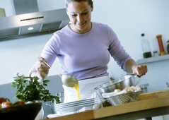 Young woman ladling soup into plate