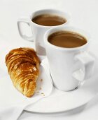 Two cups of cocoa with croissant