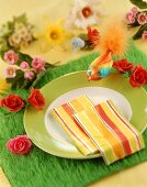 Place-setting with napkins, bird on artificial grass table mat