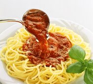 Pouring tomato sauce over spaghetti