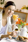 Young woman at breakfast table with orange juice