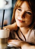 Freckled young woman with latte macchiato