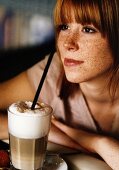 Sommersprossige junge Frau mit Latte Macchiato