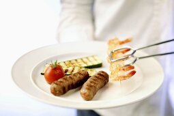 Person holding plate of various barbecued foods