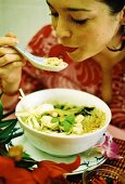 Frau isst asiatische Hühner-Gemüse-Suppe (Foto verfremdet)