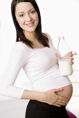 Schwangere Frau mit Milchflasche in der Hand