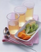 Vegetable broth in jars and a bowl of soup vegetables