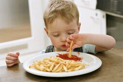 Small boy dipping chip in ketchup