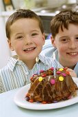 Two boys sitting in front of birthday cake