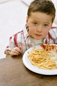 Boy sitting in front of plate of chips