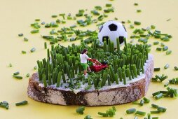 Miniature footballer mowing  bread & butter with chives