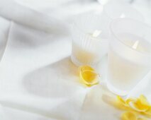 Burning candles & yellow rose petals on white table cloth