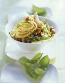 Spaghetti with fish, peanuts & mangetouts in bowl