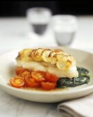 Pike-perch with potato topping on spinach and tomatoes