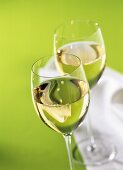 Two white wine glasses on green background with napkin