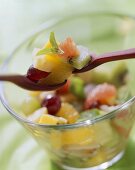 Exotic fruit salad in glass dish and on wooden spoons