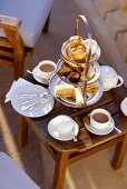 Cakes on tiered stand on small wooden table for afternoon tea 