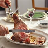 Carving leg of lamb on laid table