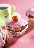 Cappuccino-Kirsch-Muffins mit rosa Glasur und Cocktailkirsche
