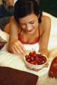 Young woman holding bowl of red cherries