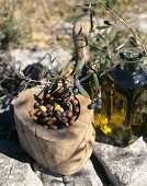 A bottle of olive oil, olives nicoise in a wooden bowl