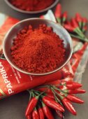 Rote Peperoncini, Paprikapulver im Schälchen und in Vepackung