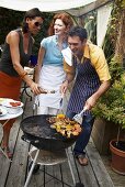 Friends barbecuing food in garden