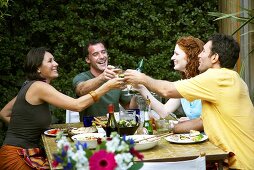 Fröhliche Leute beim Gartenfest stossen mit Weingläsern an
