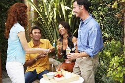 Two couples at party in garden with Sekt & fresh strawberries