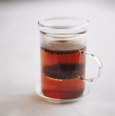 Tee mit Teeblättern im Glas